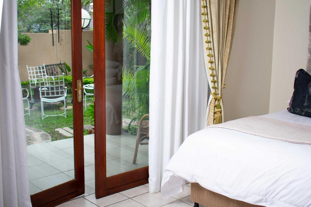 - une chambre avec une porte s'ouvrant sur une terrasse dans l'établissement Tengo guest house, à Phalaborwa