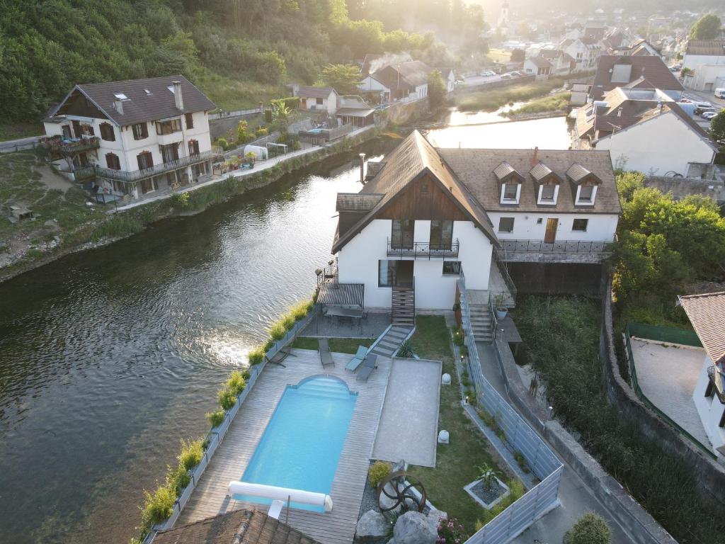 an aerial view of a house next to a river at demoiselle Loue in Ornans