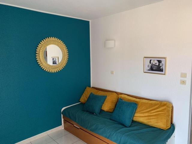 Habitación con sofá verde y espejo. en Studio Cap d'Agde avec piscine proche de la mer, en Cap d'Agde