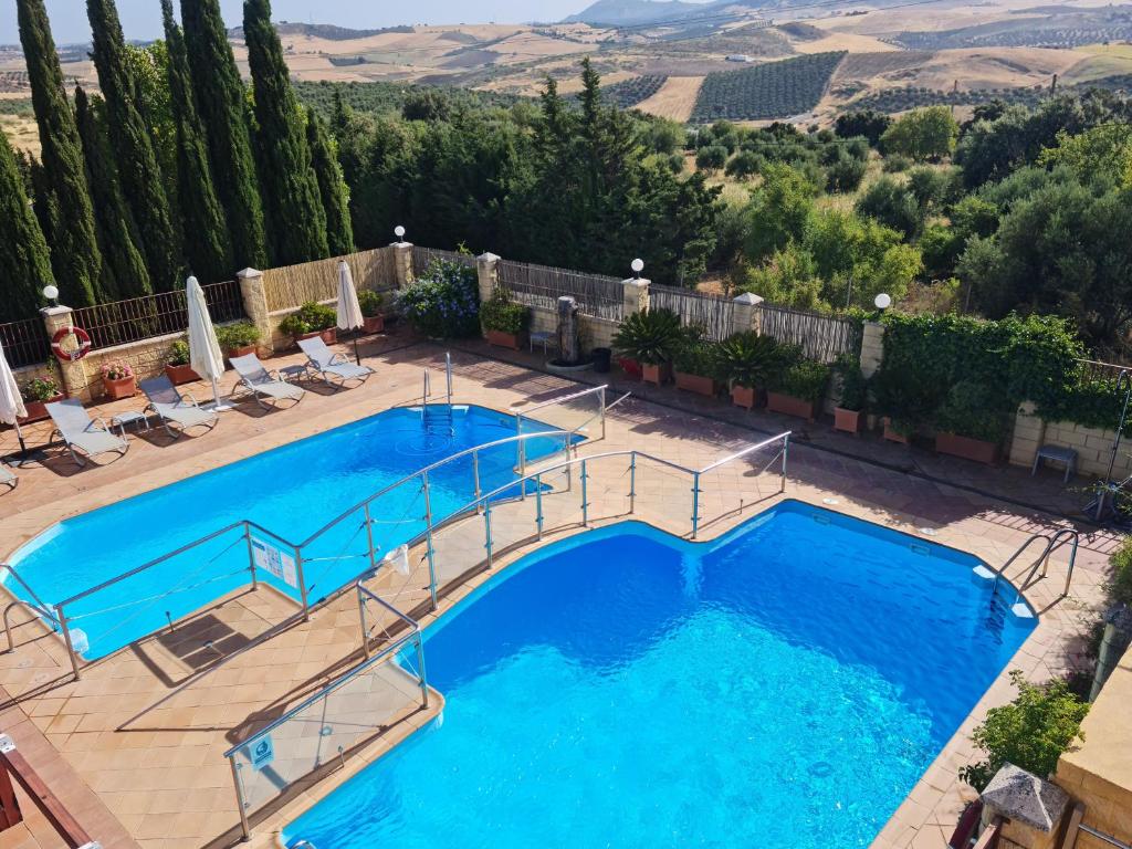 einen Blick über einen Pool mit Stühlen und Bäumen in der Unterkunft Hotel Sierra Hidalga in Ronda