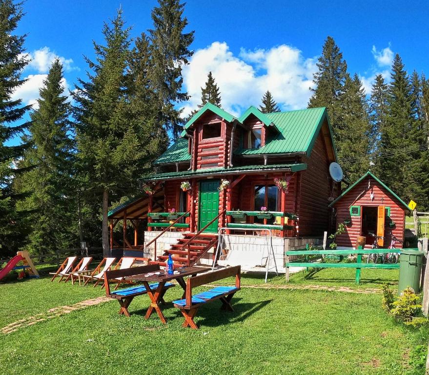 una cabaña de madera con bancos delante en Guest House Milena, en Žabljak