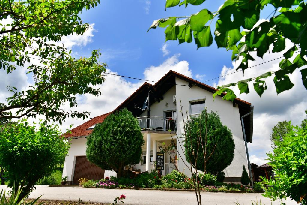 une maison blanche avec des arbres devant elle dans l'établissement Rooms Toni, à Selište Drežničko