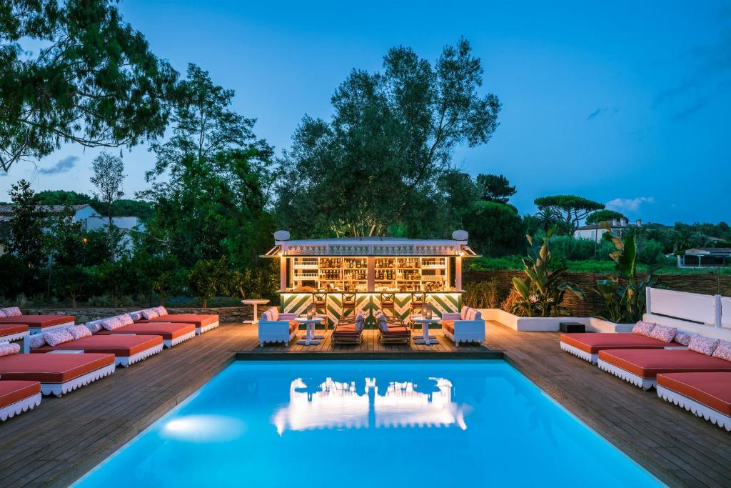 un patio con piscina y tumbonas y un edificio en Hôtel La Tartane Saint-Tropez, en Saint-Tropez