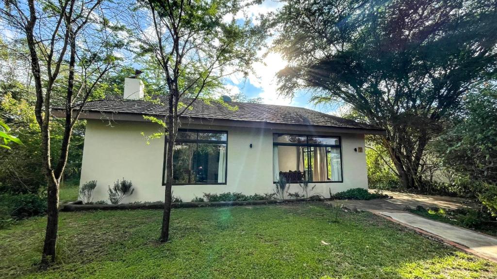 mały biały dom z drzewami na dziedzińcu w obiekcie The Senna House w mieście Nakuru