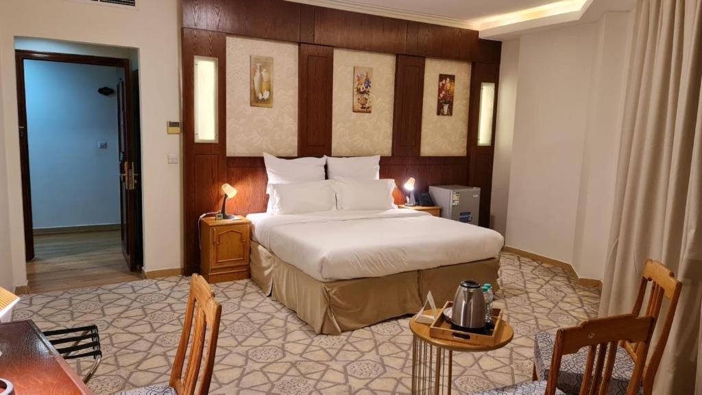 メディナにあるJiwar Al Madina Hotelのベッドとテーブルが備わるホテルルームです。