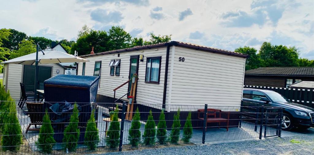 una pequeña casa blanca con un coche aparcado al lado en Ferienhaus Vienna am Kronensee, en Ostercappeln