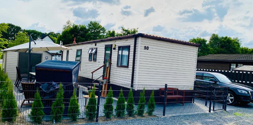 ein kleines weißes Haus mit einem Auto daneben geparkt in der Unterkunft Ferienhaus Vienna am Kronensee in Ostercappeln