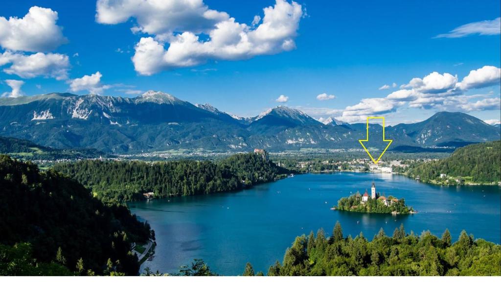 an island in the middle of a lake with mountains at Apartments Taci in Bled
