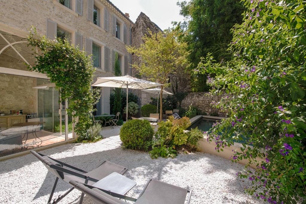 une terrasse avec une table, des chaises et un parasol dans l'établissement N15 - Les Confidences - Chambres d'hôtes, à Avignon