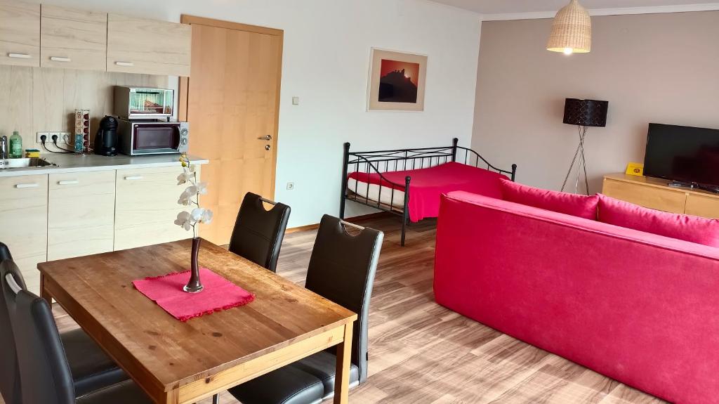 un soggiorno con tavolo e divano rosso di Appartementhaus Thermeneck a Laa an der Thaya
