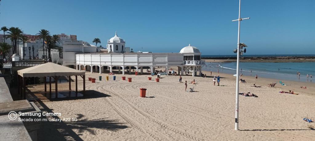 um grupo de pessoas numa praia com um edifício em Piso playa La Caleta em Cádiz