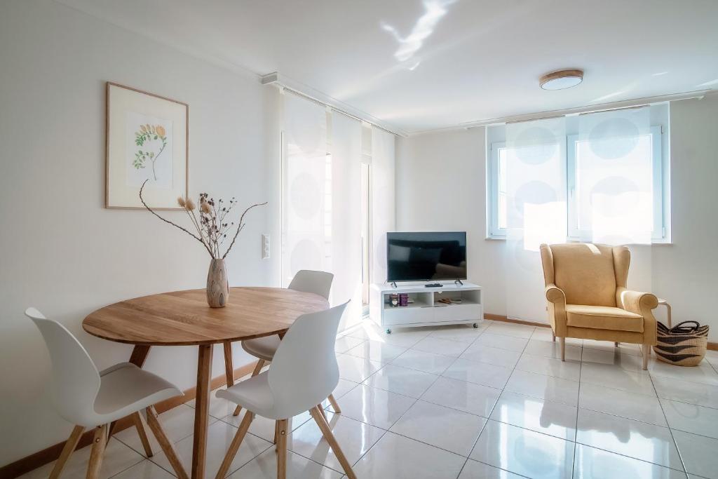 - un salon avec une table, des chaises et une télévision dans l'établissement Minusio Apartment by Quokka 360 - bright and modern flat with balcony, à Minusio