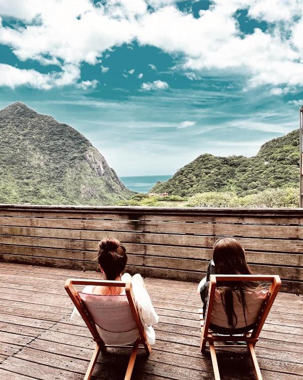 two girls sitting in chairs looking out at the mountains at Taipei Jinguashi Cloud Mountain Homestay B&amp;B in Jiufen
