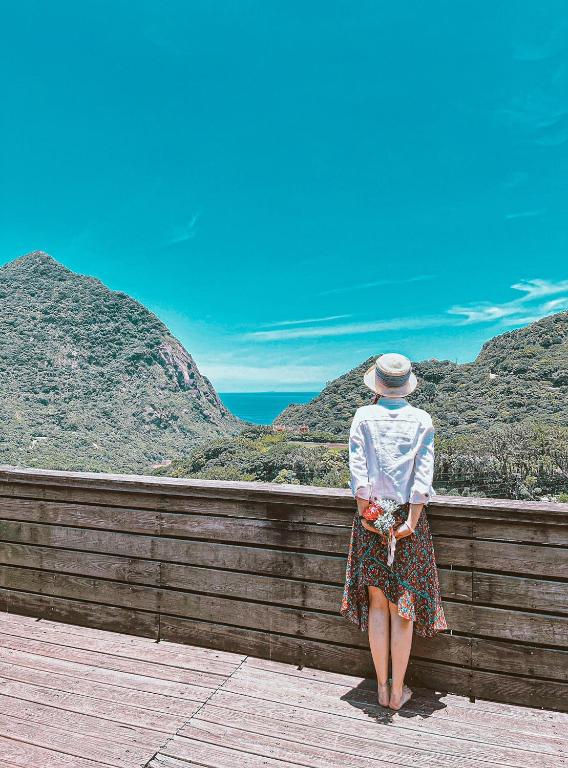 a woman standing on a fence looking at the ocean at Taipei Jinguashi Cloud Mountain Homestay B&amp;B in Jiufen