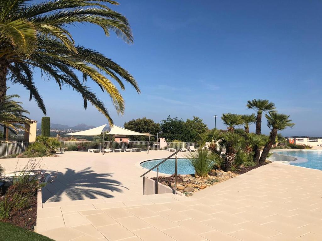 een resort met een zwembad en palmbomen bij Le Domaine Du Golf YourHostHelper in Roquebrune-sur-Argens