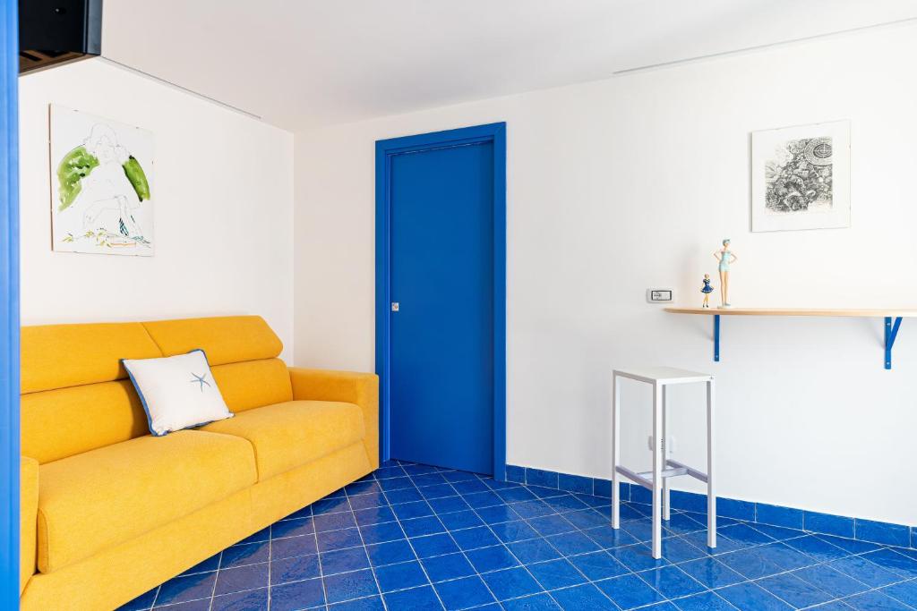 a living room with a yellow couch and a blue door at Don Leonardo - pool and wellness in Polignano a Mare