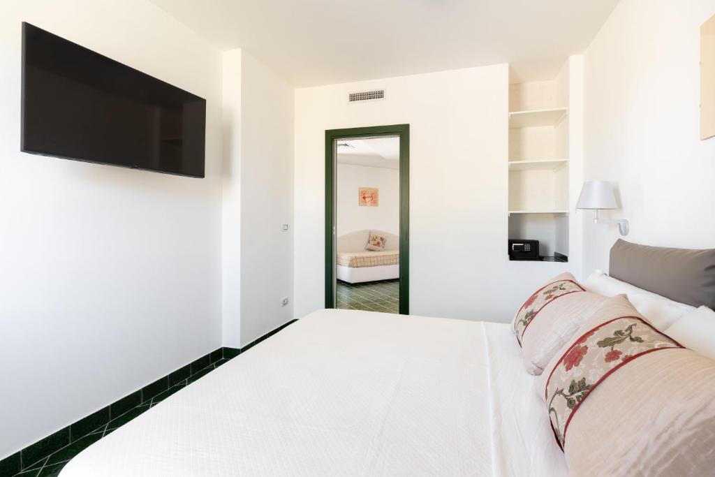 a white bedroom with a bed and a flat screen tv at Don Leonardo - pool and wellness in Polignano a Mare