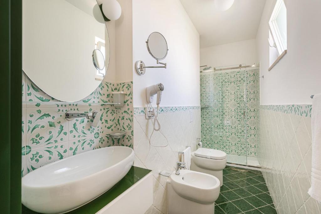 a bathroom with a sink and a toilet and a mirror at Don Leonardo - pool and wellness in Polignano a Mare