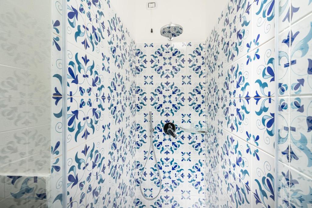 a bathroom with a blue and white patterned shower curtain at Don Leonardo - pool and wellness in Polignano a Mare