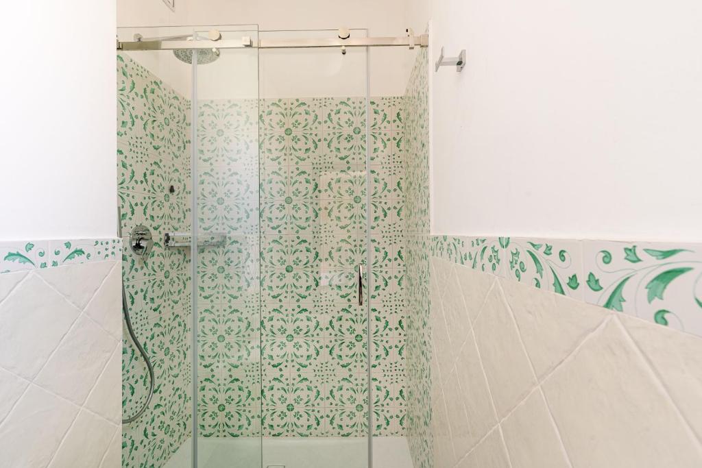 a shower with a green and white patterned shower curtain at Don Leonardo - pool and wellness in Polignano a Mare