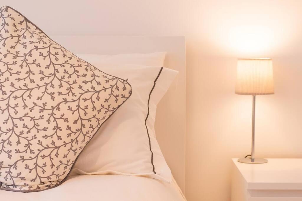 a pillow sitting on top of a bed next to a lamp at New stylish 4 bed house moments from Clacton beach in Clacton-on-Sea