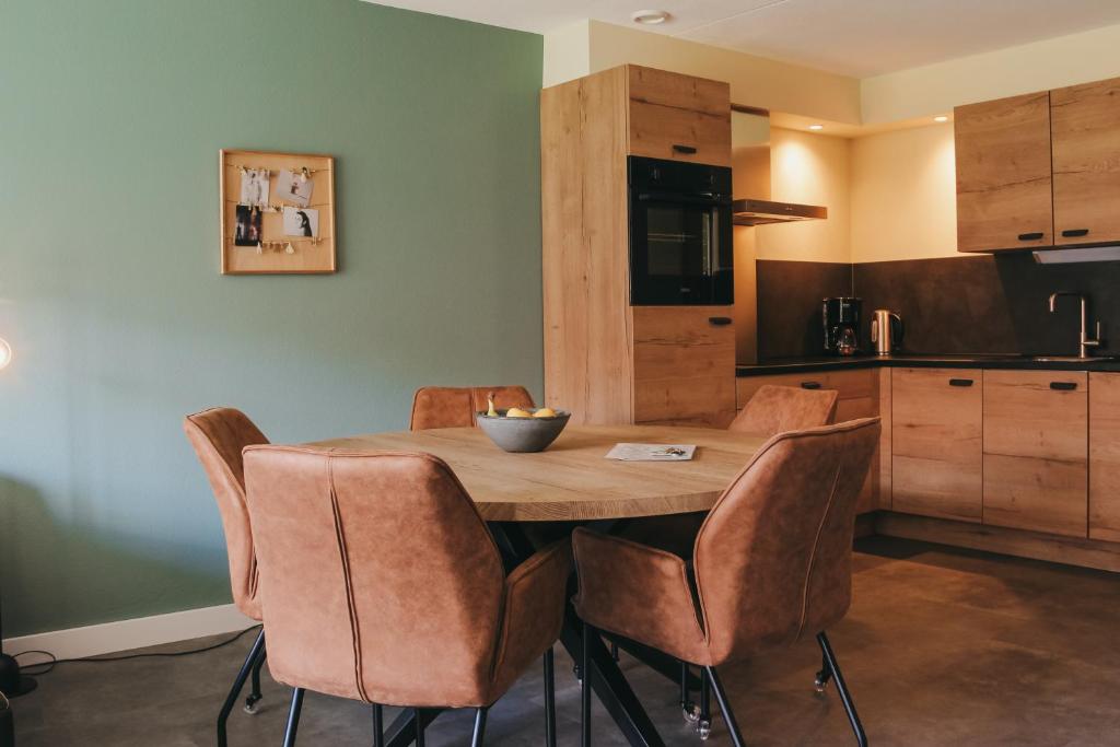 een keuken met een houten tafel en stoelen bij Appartement met bedstee in Retranchement