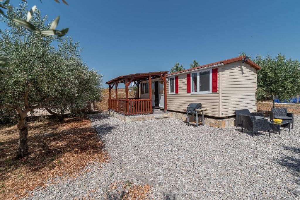 a tiny house with a porch and chairs in a yard at 'Olive grove' Camping House-near the beach in Djvulje