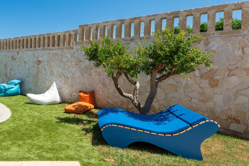 a blue bench sitting in the grass next to a tree at Don Leonardo - pool and wellness in Polignano a Mare