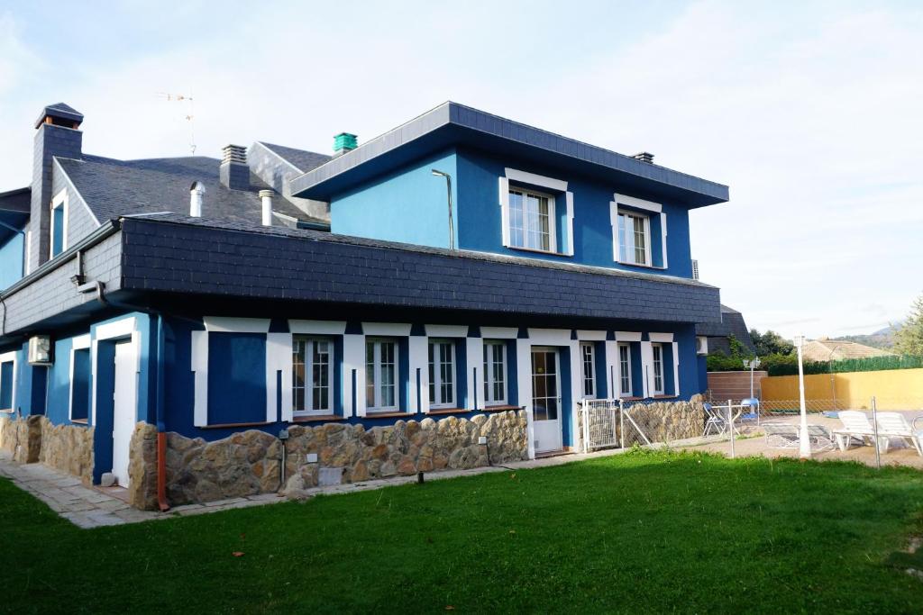 a blue and white house with a green yard at Hotel Rural La Pedriza Original in Manzanares el Real