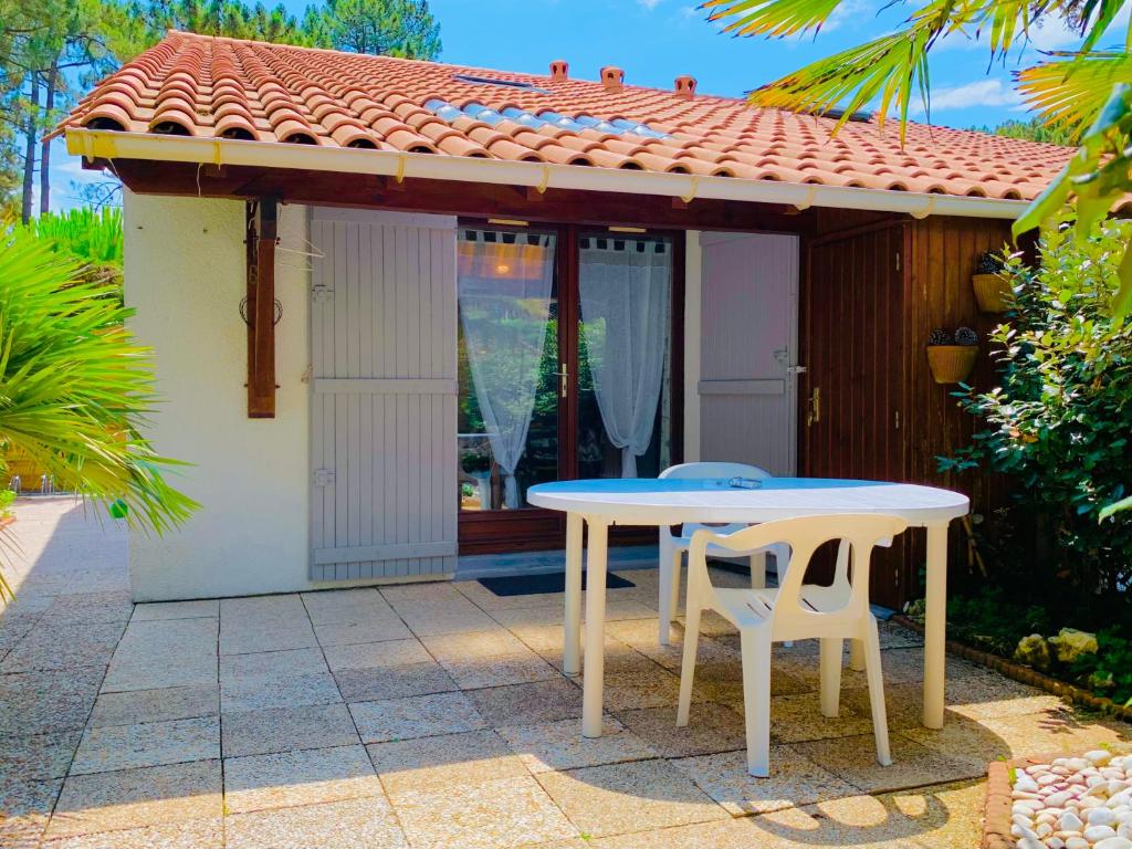a table and two chairs in front of a house at « La Palmeraie » Villa résidentielle avec piscine in La Palmyre