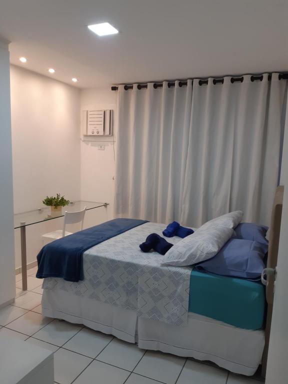 um quarto com uma cama com lençóis azuis e uma mesa em Apartamento acolhedor próximo ao mar da Jatiúca. em Maceió