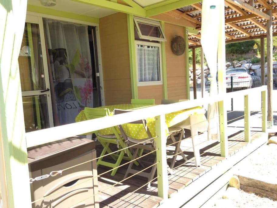 eine Veranda mit grünen Stühlen und einem Tisch in der Unterkunft Chalet à deux pas de la plage in Martigues