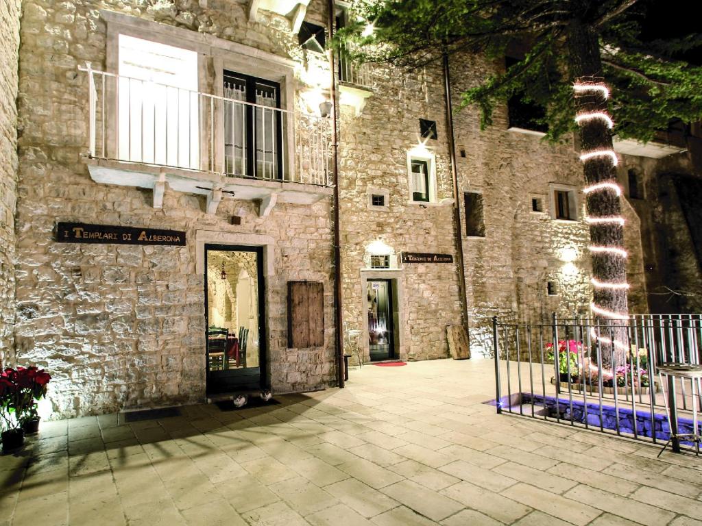 un edificio in pietra con una porta e un albero di I Templari di Alberona ad Alberona