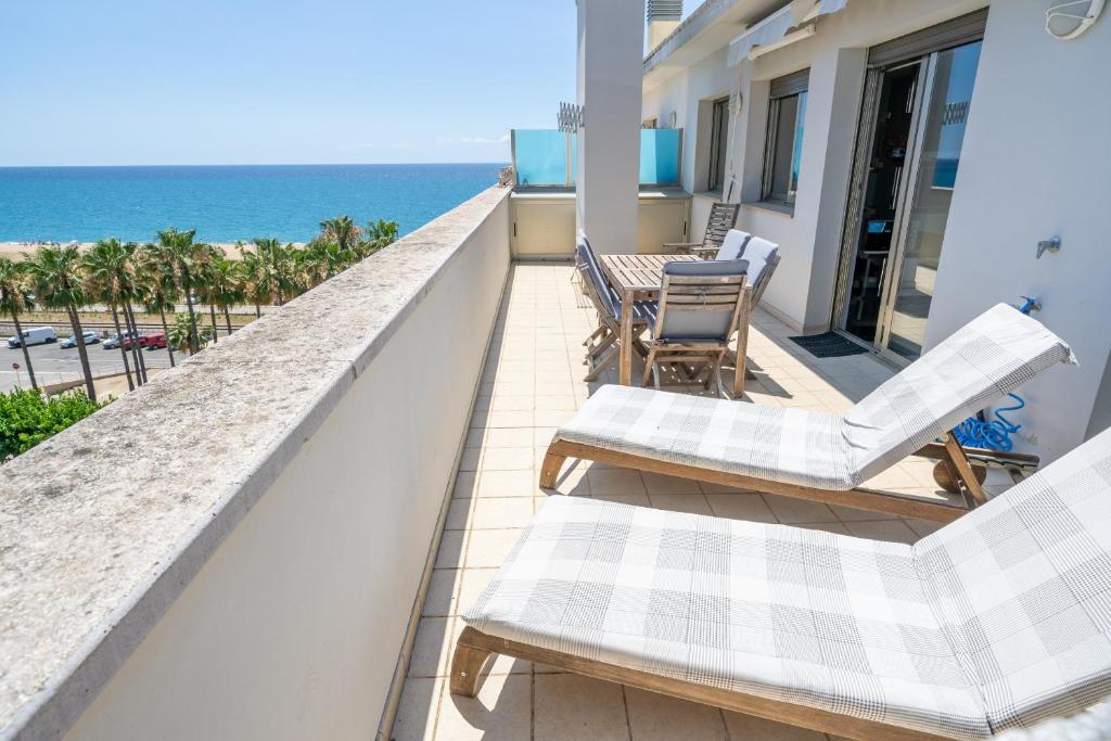 Un balcón con sillas, una mesa y el océano en HomeHolidaysRentals Blaucel - Costa Barcelona en Pineda de Mar