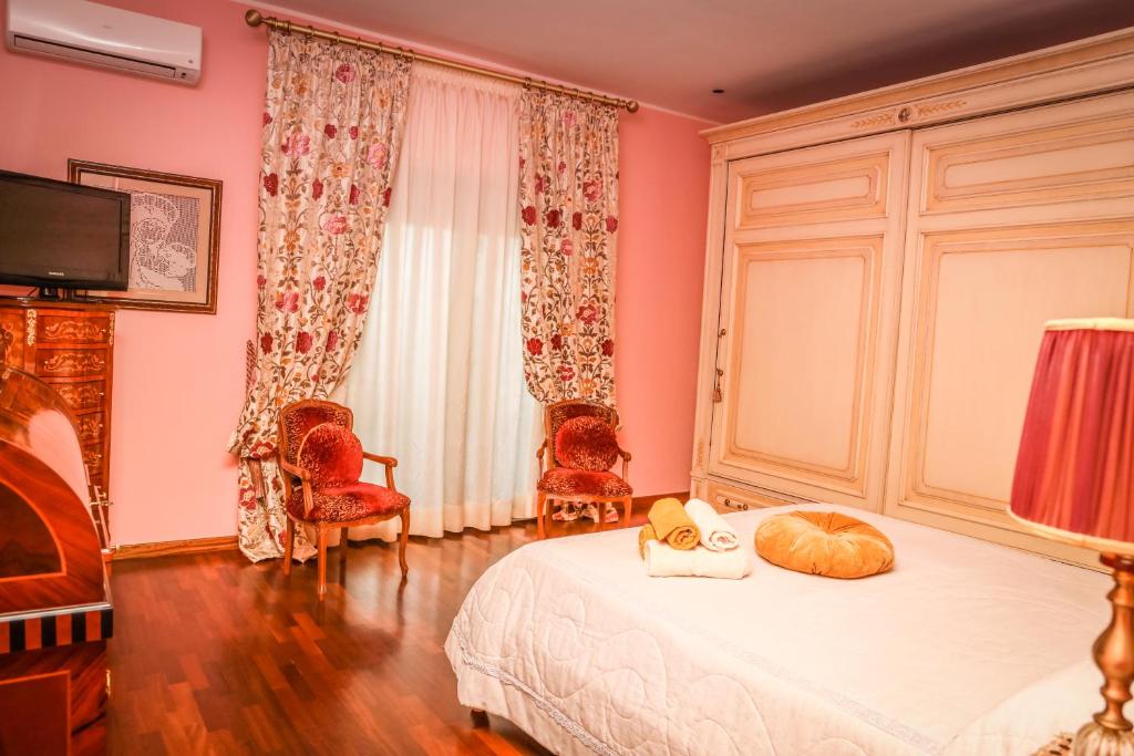 a bedroom with pink walls and a bed and chairs at IL Tetto Di Guardia in Guardia Sanframondi