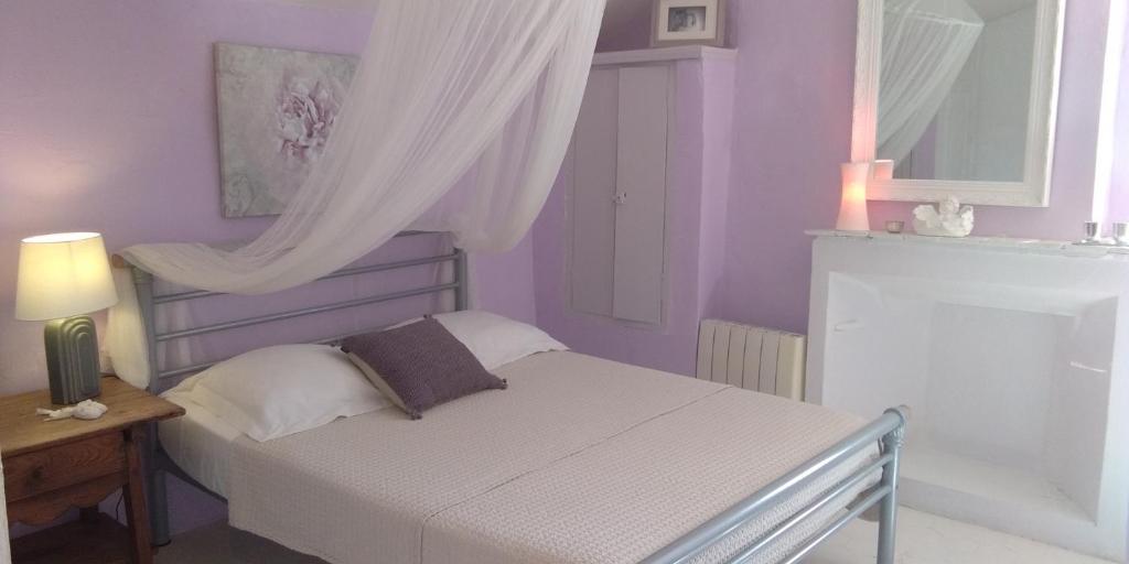 a bedroom with a bed with purple walls and a window at Bienvenue à la Source dans une Maison de Charme in Apt