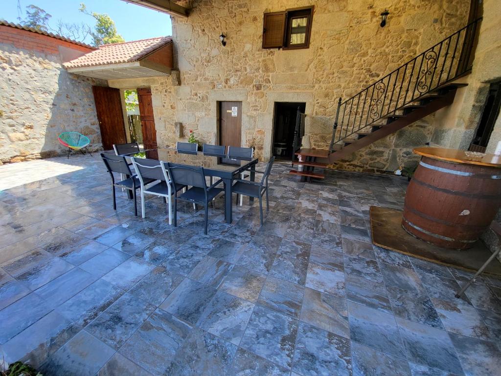 eine Terrasse mit einem Tisch, Stühlen und einem Fass in der Unterkunft Casa Maral in Pontevedra