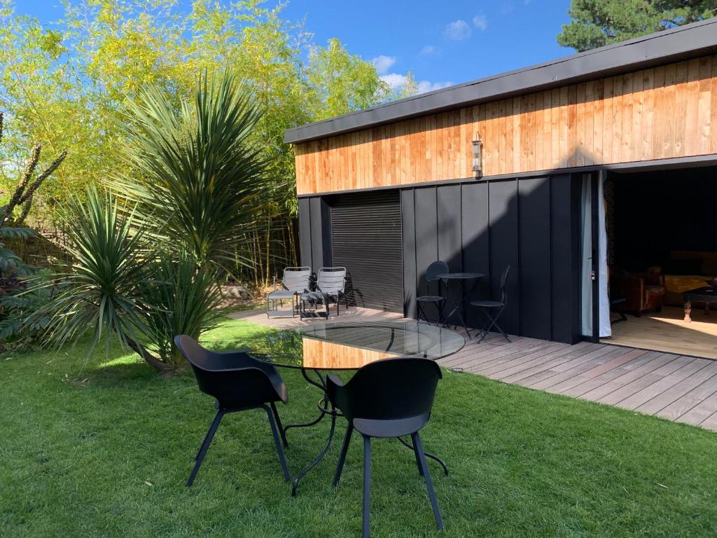 a house with a glass table and chairs on the grass at Adorable guest house au calme à 3 min du port in Vannes