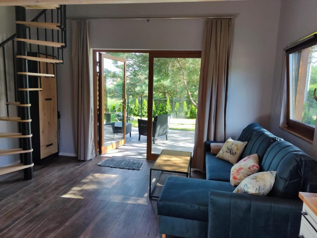 a living room with a blue couch and a sliding glass door at Domek Sworne Zacisze in Swornegacie