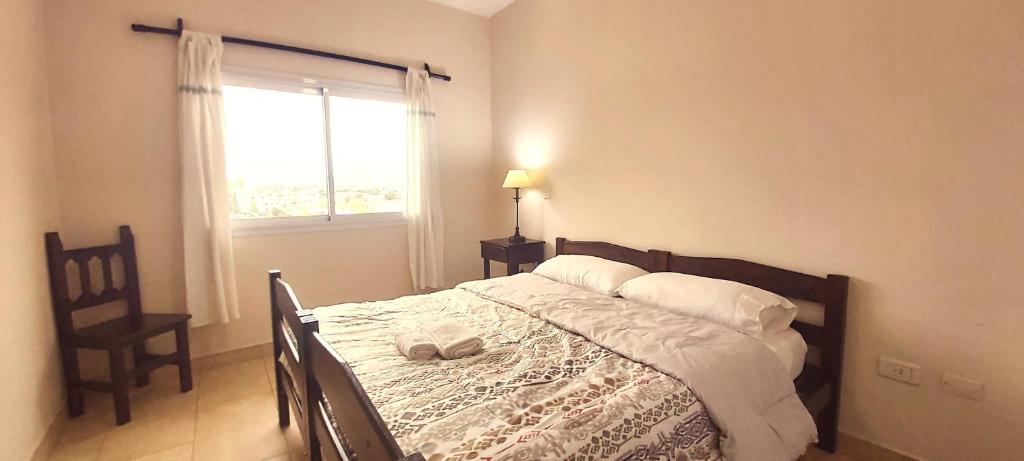 1 dormitorio con 1 cama con ventana y silla en Excelente departamento en Salta, AMANCAY en Salta