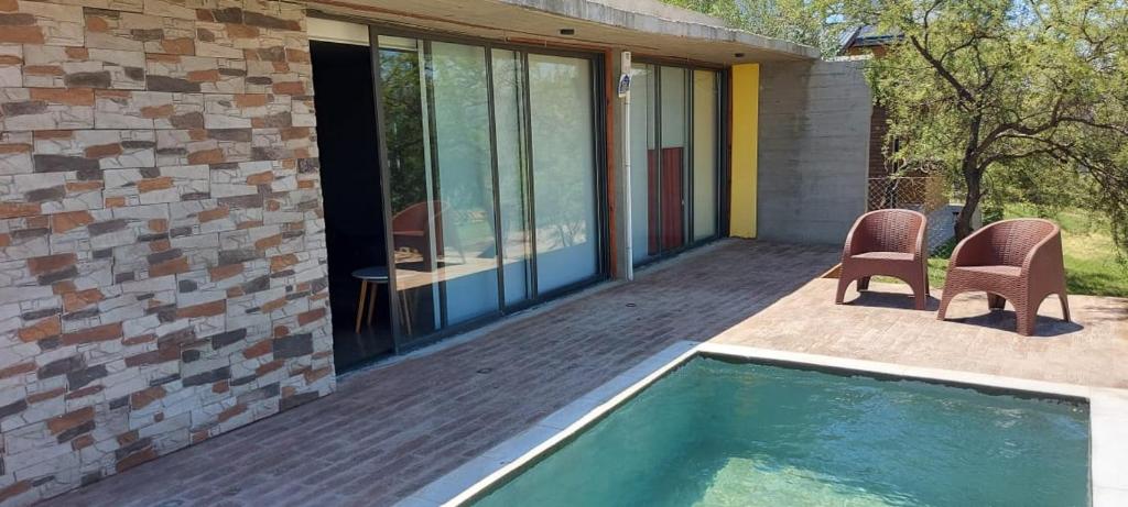 a patio with two chairs and a swimming pool at SARA HOUSE LARGE in Santa Rosa de Calamuchita