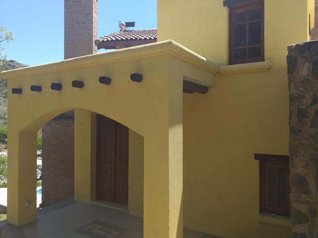 een geel huis met een boog aan de zijkant bij Casa boutique en cuesta blanca in Villa Icho Cruz