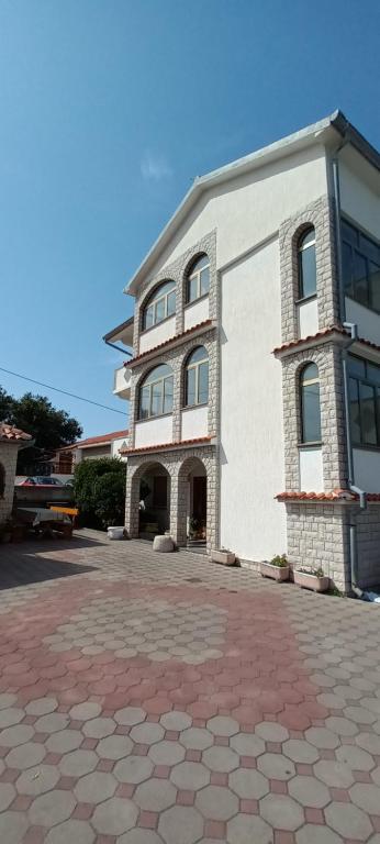 a large white building with a brick driveway at Dexi Rab in Banjol