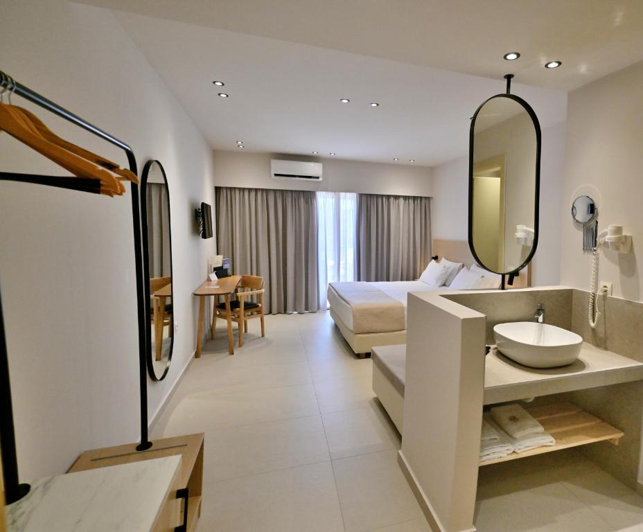 a hotel room with a bed and a sink and a mirror at Aphrodite Beach in Kissamos