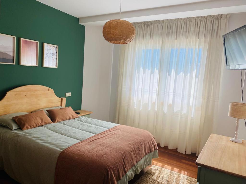 1 dormitorio con cama y pared verde en Tu hogar en el corazón de O Salnés, en Meaño