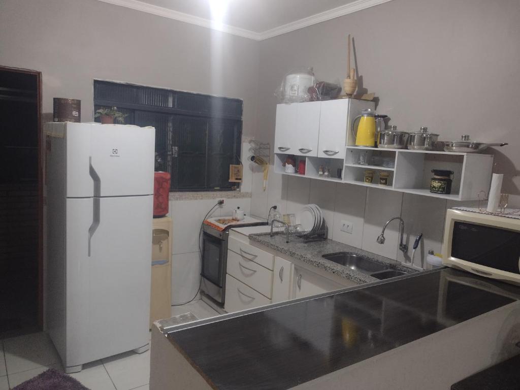 a kitchen with a white refrigerator and a sink at Nossa Casa Ambiente Familiar in Águas de São Pedro