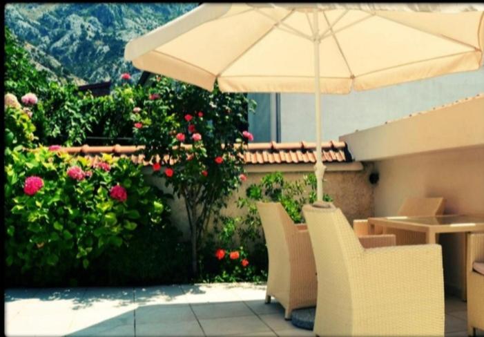a patio with an umbrella and chairs and flowers at Apartments Kotor Sunrise in Kotor
