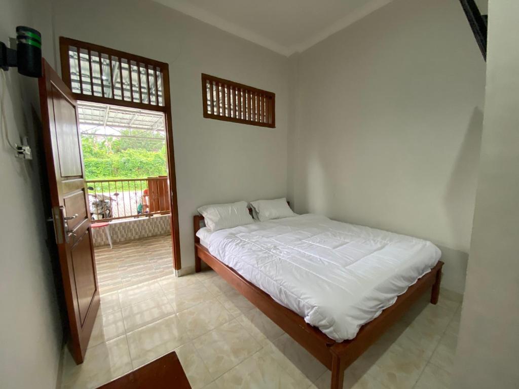 ein Schlafzimmer mit einem Bett in einem Zimmer mit einem Fenster in der Unterkunft OYO 91419 Hotel Mulia Bangka in Pangkalpinang