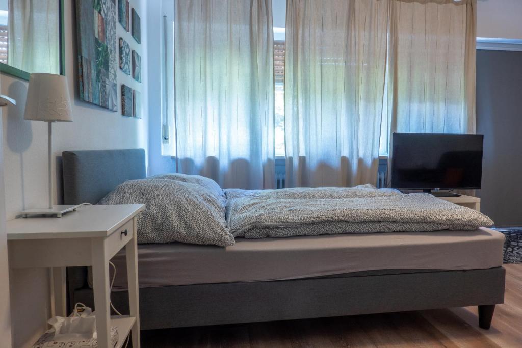 een slaapkamer met een bed, een bureau en een televisie bij Kleines Souterrain Apartment direkt am Park in Wiesbaden