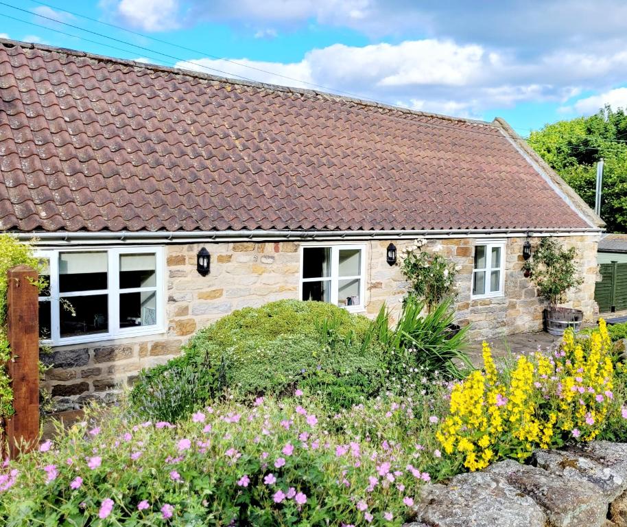 una casa de campo de piedra con flores delante en Underhill Holidays - Underhill Holiday Cottage en Whitby